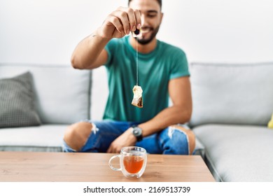 Young Arab Man Smiling Confident Holding Tea Bag At Home