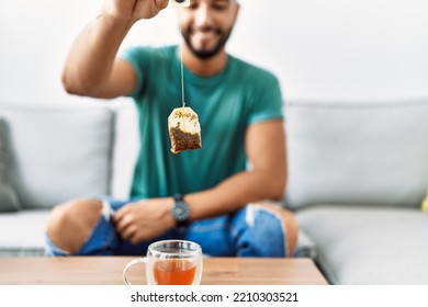 Young Arab Man Smiling Confident Holding Tea Bag At Home