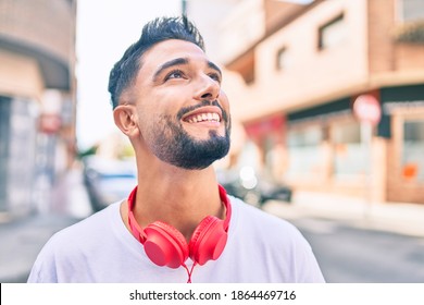 Young Arab Man Smiling Happy Using Headphones Walking At The City.