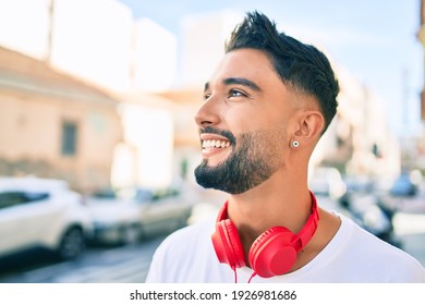 Young Arab Man Smiling Happy Using Headphones Walking At The City.