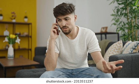 Young arab man talking on smartphone with unhappy expression at home