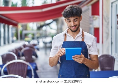 Young arab man waiter using touchpad working at restaurant - Powered by Shutterstock