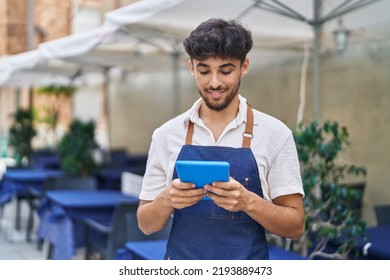 Young arab man waiter using touchpad working at restaurant - Powered by Shutterstock