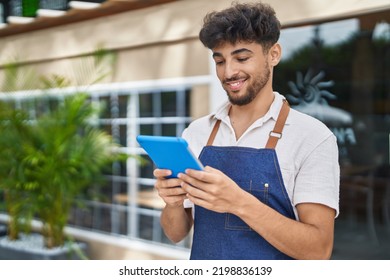 Young arab man waiter using touchpad working at restaurant - Powered by Shutterstock