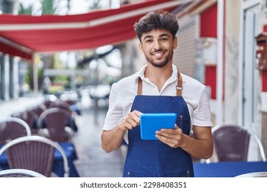 Young arab man waiter using touchpad working at restaurant - Powered by Shutterstock