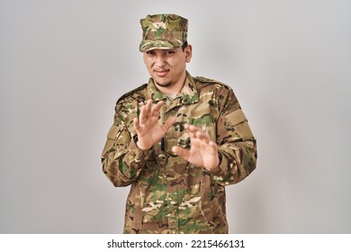 Young Arab Man Wearing Camouflage Army Uniform Disgusted Expression, Displeased And Fearful Doing Disgust Face Because Aversion Reaction. 