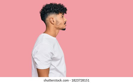 Young Arab Man Wearing Casual White T Shirt Looking To Side, Relax Profile Pose With Natural Face And Confident Smile. 