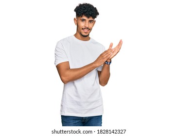 Young Arab Man Wearing Casual White T Shirt Clapping And Applauding Happy And Joyful, Smiling Proud Hands Together 