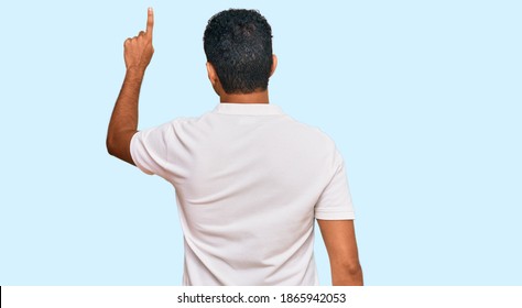 Young Arab Man Wearing Casual Clothes Posing Backwards Pointing Ahead With Finger Hand 