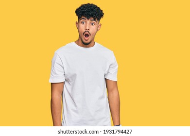 Young Arab Man Wearing Casual White T Shirt In Shock Face, Looking Skeptical And Sarcastic, Surprised With Open Mouth 