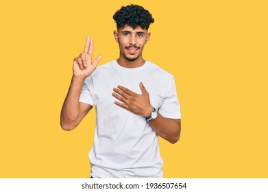 Young Arab Man Wearing Casual White T Shirt Smiling Swearing With Hand On Chest And Fingers Up, Making A Loyalty Promise Oath 