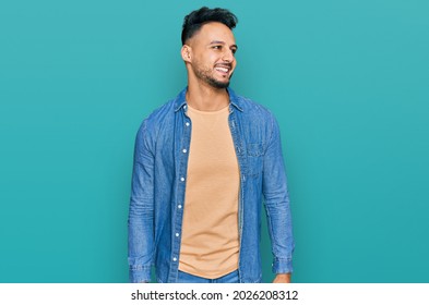 Young Arab Man Wearing Casual Clothes Looking Away To Side With Smile On Face, Natural Expression. Laughing Confident. 