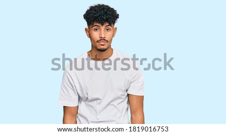 Young arab man wearing casual white t shirt looking sleepy and tired, exhausted for fatigue and hangover, lazy eyes in the morning. 