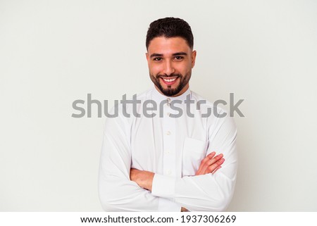 Young arab man wearing typical arab clothes isolated on white background who feels confident, crossing arms with determination.