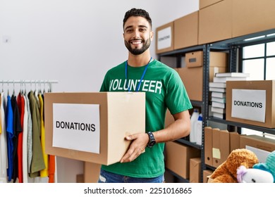 Young arab man wearing volunteer uniform holding donations box at charity center - Powered by Shutterstock