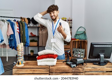 Young arab man working as manager at retail boutique holding alarm tag stressed and frustrated with hand on head, surprised and angry face 