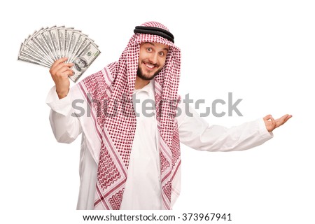 Young Arab spreading a stack of money and making a welcoming gesture with his hand isolated on white background