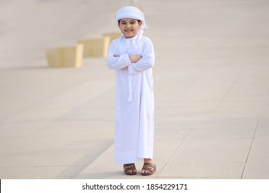 Young Arab student smiling wearing Ghutra Kandura dish dash in the Middle East. Full body portrait shot of Arabic boy