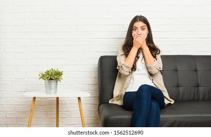 Young Arab Woman Sitting On The Sofa Shocked Covering Mouth With Hands.