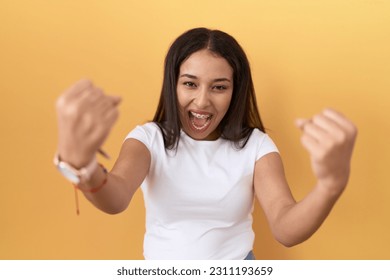 Young arab woman wearing casual white t shirt over yellow background angry and mad raising fists frustrated and furious while shouting with anger. rage and aggressive concept.  - Shutterstock ID 2311193659