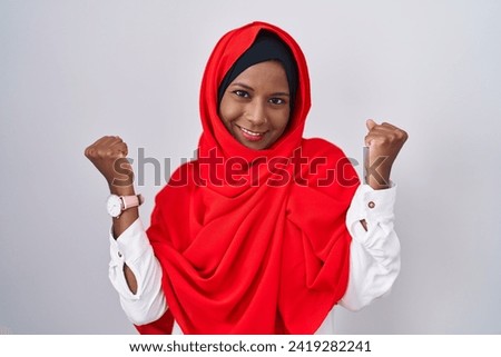Young arab woman wearing traditional islamic hijab scarf celebrating surprised and amazed for success with arms raised and eyes closed. winner concept. 
