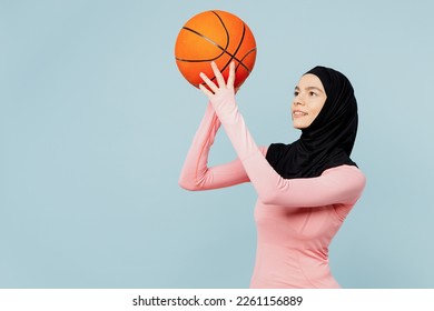 Young arabian asian muslim fitness trainer sporty woman wear pink abaya hijab spend time in home gym hold throw basketball ball isolated on plain blue background studio Workout sport fit abs concept - Powered by Shutterstock