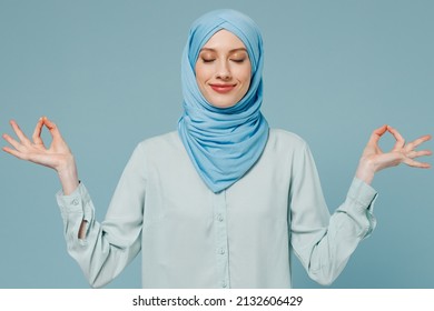 Young arabian asian muslim woman in abaya hijab hold spreading hands in yoga om aum gesture relax meditate calm down isolated on plain blue background People uae middle eastern islam religious concept - Powered by Shutterstock