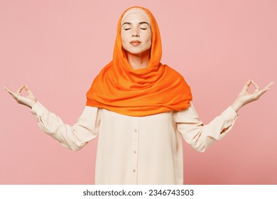 Young arabian asian muslim woman wear orange abaya hijab hold spreading hands in yoga om aum gesture relax meditate isolated on plain pink background studio. Uae middle eastern islam religious concept - Powered by Shutterstock