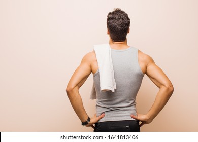 young arabian man feeling confused or full or doubts and questions, wondering, with hands on hips, rear view. sport concept - Powered by Shutterstock