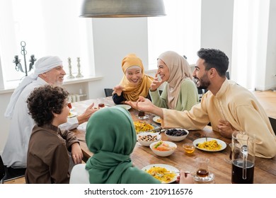 Young Arabian Man Talking To Cheerful Multicultural Muslim Family During Dinner