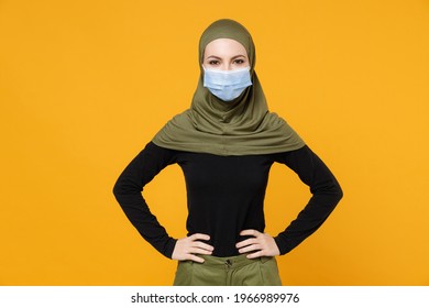 Young arabian muslim woman in hijab green clothes sterile face mask to safe from coronavirus virus covid-19 standing with arms akimbo isolated on yellow background. People religious lifestyle concept - Powered by Shutterstock