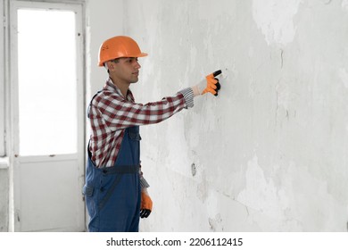 Young Arabic Man Over Grey Wall Wearing Contractor Uniform And Safety Helmet Pointing And Showing With Finger To The Wall Empty Space, Copy Space