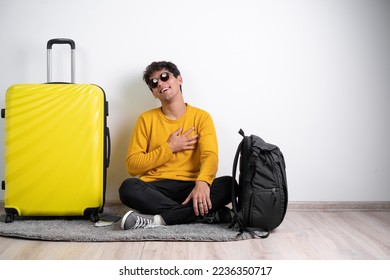 Young arabic man ready to go to travel has friendly expression, pressing hand to chest. Love concept and travel. Copy space