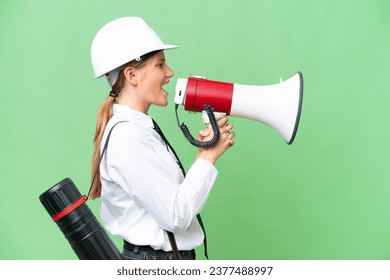 Young architect caucasian woman with helmet and holding blueprints over isolated background shouting through a megaphone - Powered by Shutterstock