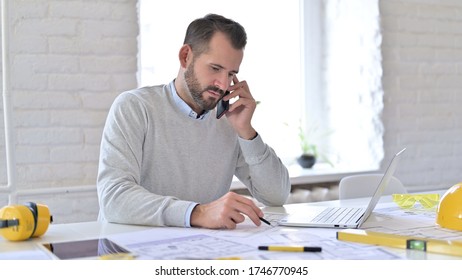 Young Architect with Documents Talking on Smartphone