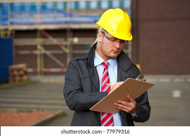 young architect or inspector make some notes, office building as background
