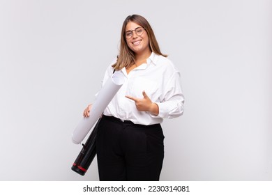 young architect woman smiling cheerfully, feeling happy and pointing to the side and upwards, showing object in copy space - Powered by Shutterstock