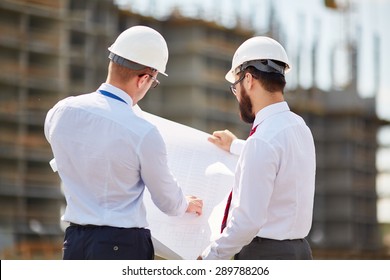 Young Architects With Blueprint Discussing Sketch Of New Building Construction