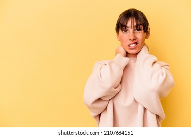 Young Argentinian woman isolated on yellow background touching back of head, thinking and making a choice.