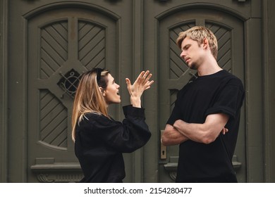 Young arguing sad couple two friends family man woman in casual clothes screaming scolding together walking outdoor near door of home. Woman yelling at man. Couple arguing, having relationship problem
