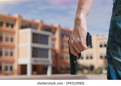 Young armed man holds pistol in hand in public place near high school. Gun control concept.