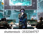 Young army conscript checking mission data and details on a hologram projection, studying operation briefings in military command center. Soldier looks at CCTV radar imagery on 3d visualization.