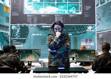Young army conscript checking mission data and details on a hologram projection, studying operation briefings in military command center. Soldier looks at CCTV radar imagery on 3d visualization.