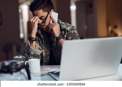 Young Army Soldier Having Headache While Talking On Mobile Phone And Working At Desk Office. 