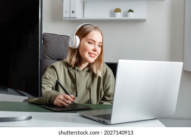 Young artist graphic designer woman drawing on digital graphic tablet by Stylus pen using laptop pc monitor at home office interior. Freelance designer in headphones studying or working remotely - Powered by Shutterstock