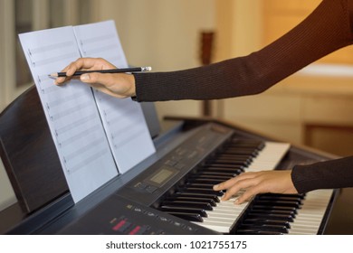 Young Artist Musician Woman Practices And Trains Skills, Compose Writing Notes By Pencil. Teaching Student To Play The Piano In Music Room. 