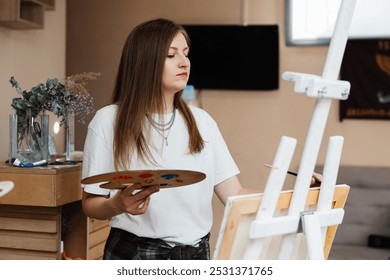 Young artist painting on canvas with palette in a bright studio - Powered by Shutterstock