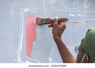 A young artist passionately painting a vibrant mural on a city wall, adding a burst of color to the urban landscape. - Powered by Shutterstock