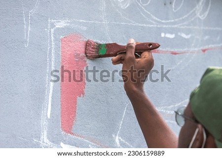 A young artist passionately painting a vibrant mural on a city wall, adding a burst of color to the urban landscape.