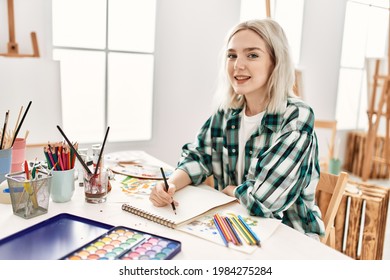 Young Artist Student Girl Smiling Happy Painting Sitting On Desk At Art Studio.